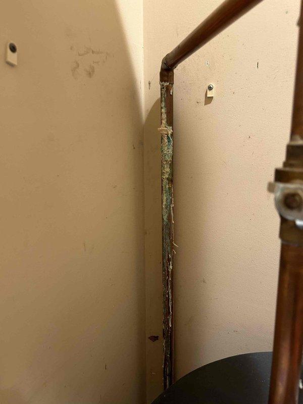 Responded to emergency same-day service call for water leak originating from water heater located in main floor closet. Upon arrival, identified active dripping condition at water heater connections. Inspection revealed significant moisture damage to surrounding wall structure and corner framing, with visible deterioration, dark discoloration, and blue-green staining indicative of prolonged water exposure and potential microbial growth.

Evaluated water filtration system and associated copper piping upstream of water heater. Identified leak source at connection points near filter housing assembly. Shut off water supply using existing ball valves to isolate affected section. Assessed condition of copper piping, brass fittings, and PEX connections throughout the system, noting age-related patina and corrosion at multiple junction points.

Tightened compromised connections and replaced deteriorated fittings as necessary. Verified integrity of water filter housing, mounting bracket, and pr