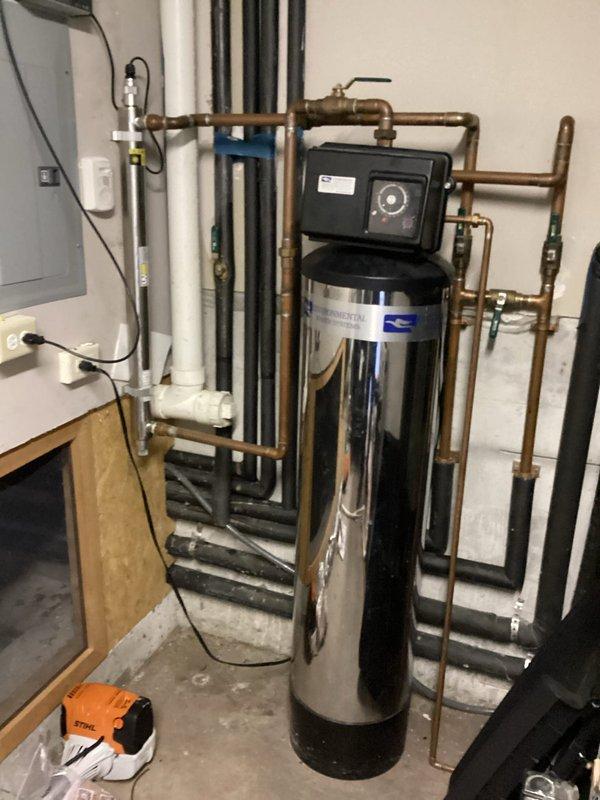 Performed a water leak locate on the domestic water supply line connected to the desuperheater and identified moisture and staining at the insulated copper piping and fittings near the mechanical equipment. Inspected the adjacent water softener and associated shutoff valves and piping, documenting the affected areas with photos for repair planning.