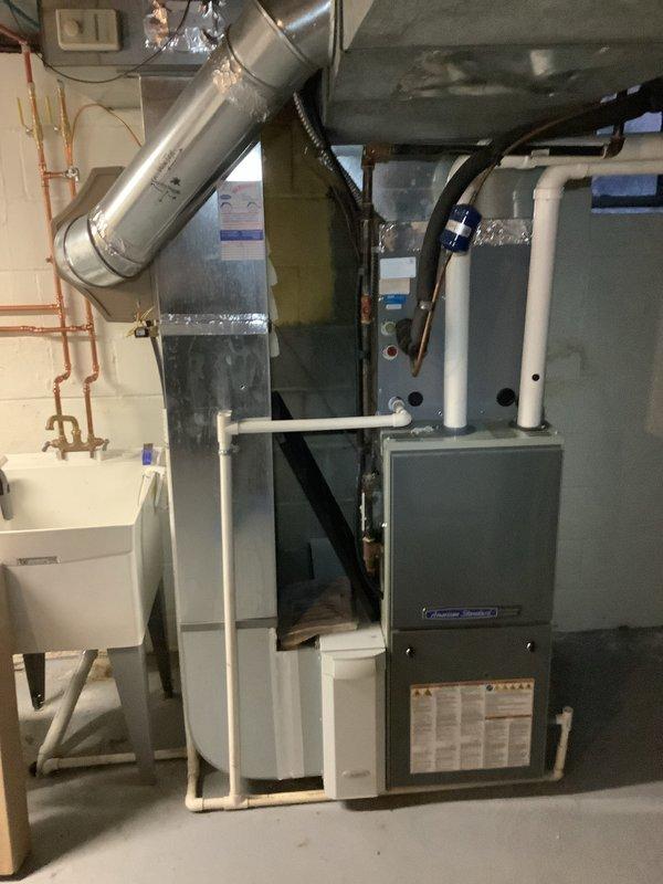 Completed installation of American Standard 90% efficient furnace and AC system in residential basement. System includes properly sealed ductwork with metallic tape at all seams and connections, and PVC ventilation piping. Final testing confirmed proper operation with supply air temperature reaching 648°F during heat cycle verification.