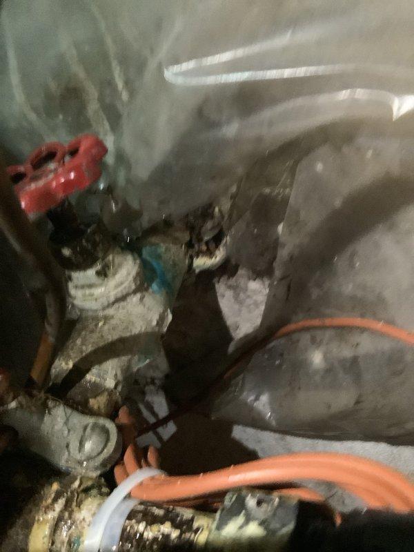 Responded to customer-reported water leak at main meter. Inspected valve assembly in confined space showing signs of corrosion and mineral buildup. Observed significant water damage to cabinet base with warped and deteriorated wood. Replaced faulty main water valve to resolve leak issue.