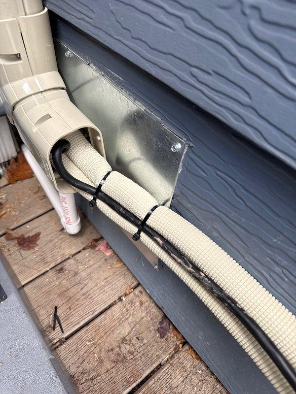 Successfully installed a Daikin single-head mini-split system with the outdoor condenser properly mounted on a concrete pad on the customer's wooden deck. Removed existing wall heater and covered flue with sheet metal as requested, with customer agreeing to complete additional repairs. Professional line-set installation includes proper wall penetration with weather-sealed cover plate and secured PVC line covers.
