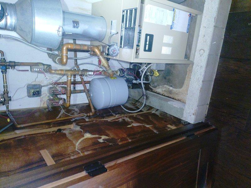 Replaced faulty pressure reducing valve and installed new Extrol expansion tank on customer's hydronic heating system after identifying water damage to surrounding cabinetry. System required complete drain down and refill procedure to restore proper operation and prevent further leakage issues.