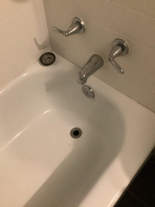 Inspected basement bathtub leaking from underneath. Discovered standing water with significant corrosion on pipes below the tub. Documented condition with photos showing deteriorated plumbing components and drain assembly. Reported findings to landlord for approval of necessary repairs.
