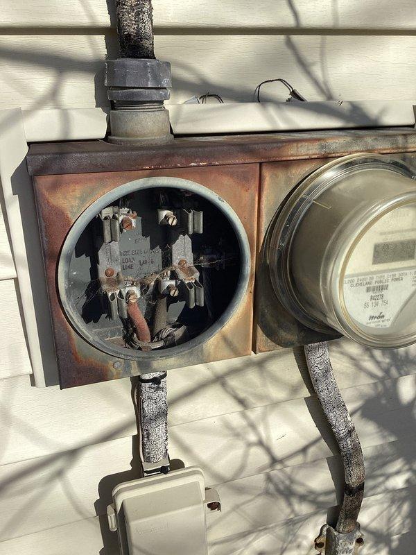 Diagnosed power outage issue at residence with no electricity to main panel. Upon inspection, discovered damaged weatherhead connection at meter base showing significant oxidation and exposed wiring components. Replaced weathered service entrance conductor connections and secured loose wiring in main distribution panel to restore electrical service to home.