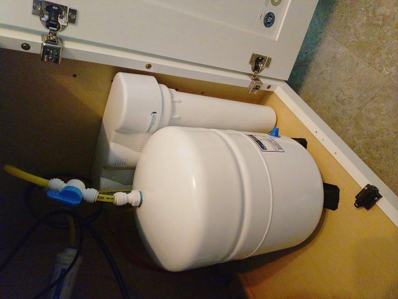 Completed installation of water softener system with digital control unit and water filtration system including reverse osmosis drinking water components. Successfully connected the ice maker line to the RO system and decommissioned existing valve. Installation included mounting dual filter canisters with PVC connections and proper integration with existing plumbing infrastructure.