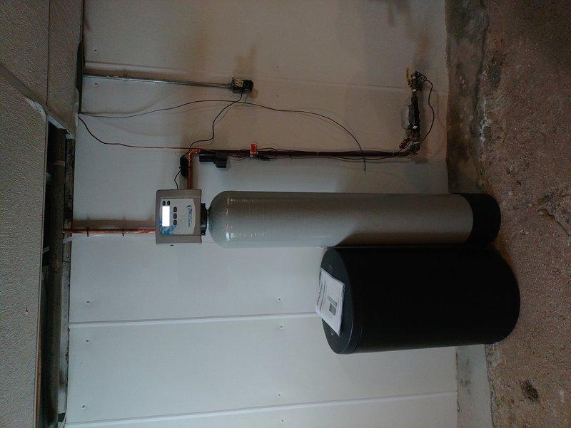 Completed installation of water softener system with digital control unit and water filtration system including reverse osmosis drinking water components. Successfully connected the ice maker line to the RO system and decommissioned existing valve. Installation included mounting dual filter canisters with PVC connections and proper integration with existing plumbing infrastructure.