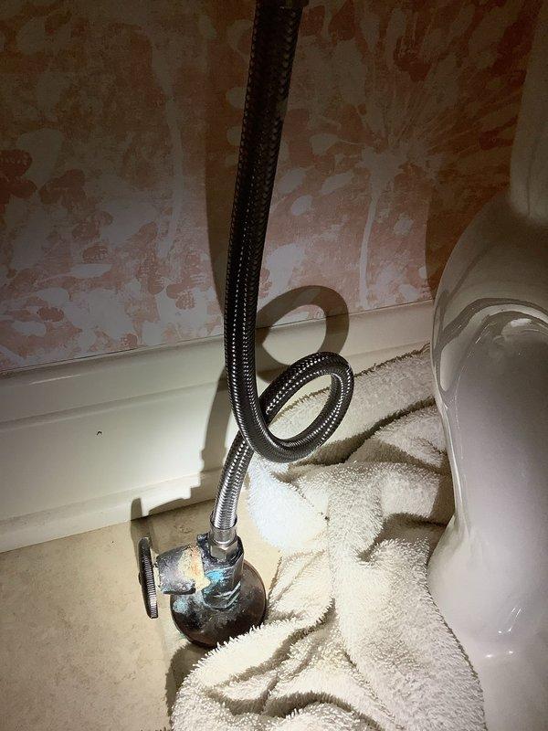 Responded to customer's report of toilet leak. Inspected plumbing fixtures and found corrosion on water supply valve with visible mineral buildup at connection point. Diagnosed leak originating from deteriorated supply line connection to shut-off valve. Replaced corroded valve and installed new braided supply line, ensuring proper connection to toilet tank. Tested system for leaks and confirmed proper operation before completion.