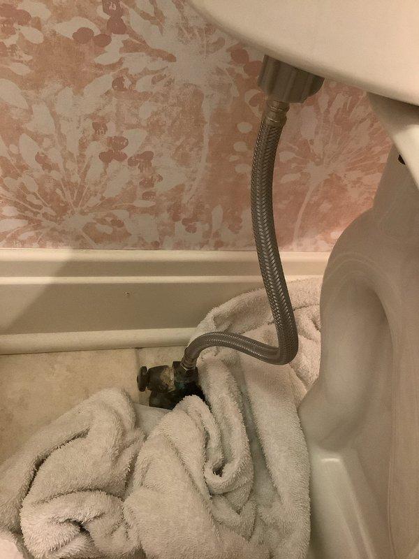 Responded to customer's report of toilet leak. Inspected plumbing fixtures and found corrosion on water supply valve with visible mineral buildup at connection point. Diagnosed leak originating from deteriorated supply line connection to shut-off valve. Replaced corroded valve and installed new braided supply line, ensuring proper connection to toilet tank. Tested system for leaks and confirmed proper operation before completion.