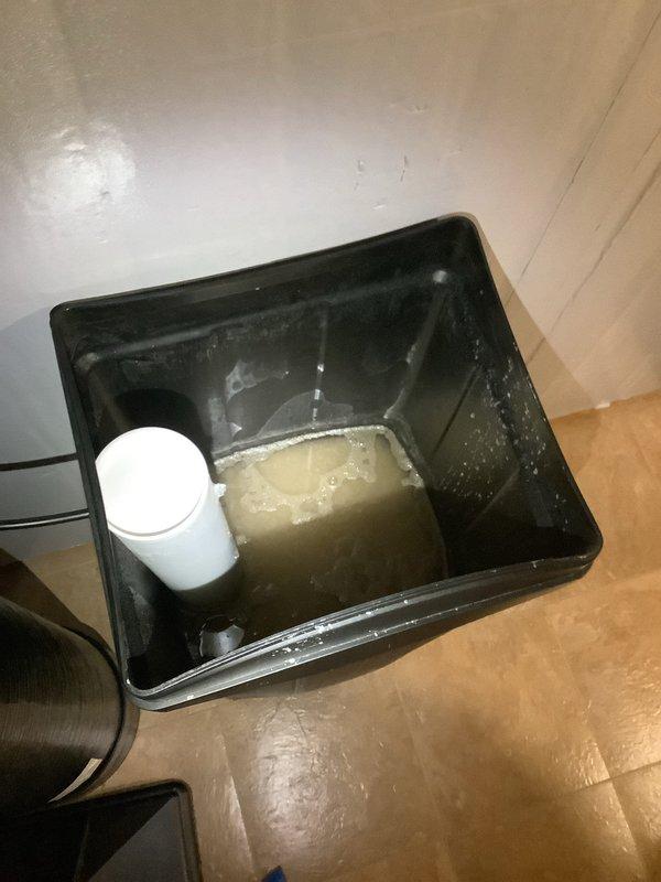 Inspected tankless water heater system and assessed customer's water softener holding tank, which contained brown sludge as reported by homeowner. Documented condition of holding tank through photo evidence showing cloudy, yellowish liquid with sediment buildup. Scheduled follow-up appointment with Craig to address the water softener issues, as customer opted to postpone the tankless water heater flush service until spring.