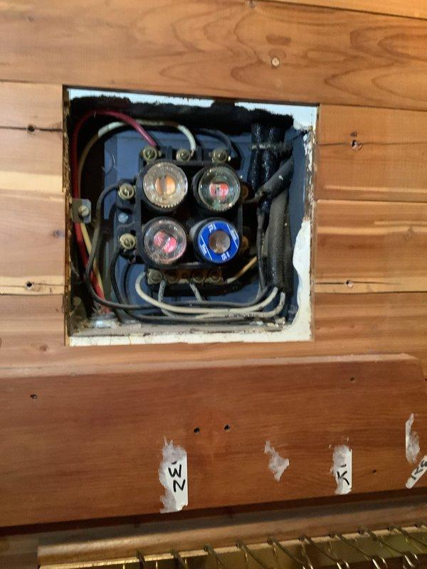 Completed a comprehensive service upgrade involving installation of dual service panels and a 100-amp transfer switch. Removed outdated fuse panel system embedded in wooden wall paneling and replaced with modern circuit breaker panels. Upgraded exterior electrical connections at the meter and junction box on brick exterior wall, ensuring proper connection to utility power lines.