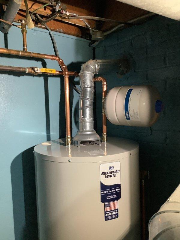 Successfully installed a new 50-gallon Bradford White water heater in basement utility area. Installed required code-compliant thermal expansion tank. System includes properly connected copper piping and metal ventilation with appropriate insulation.