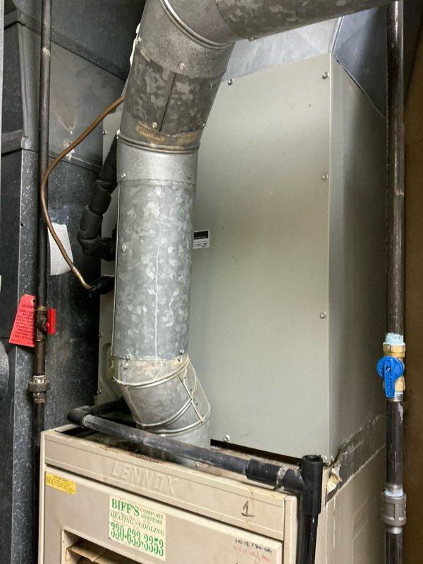Performed estimate for replacement of two 34-year-old furnaces, one of which has a cracked heat exchanger. Inspection of the existing Lennox system revealed aging ductwork with multiple connections and joints that would need to be addressed during replacement. Photos documented the current installation configuration including the furnace, supply/return connections, and associated control equipment.