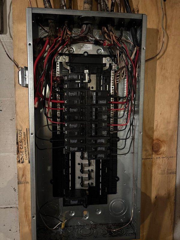 Completed 100 amp 30-circuit panel replacement as requested. Installed new breaker panel on wooden wall with proper wiring configuration, connecting all necessary red and black electrical wires to appropriate circuit breakers. GFCI outlet was installed below the panel in compliance with code requirements.