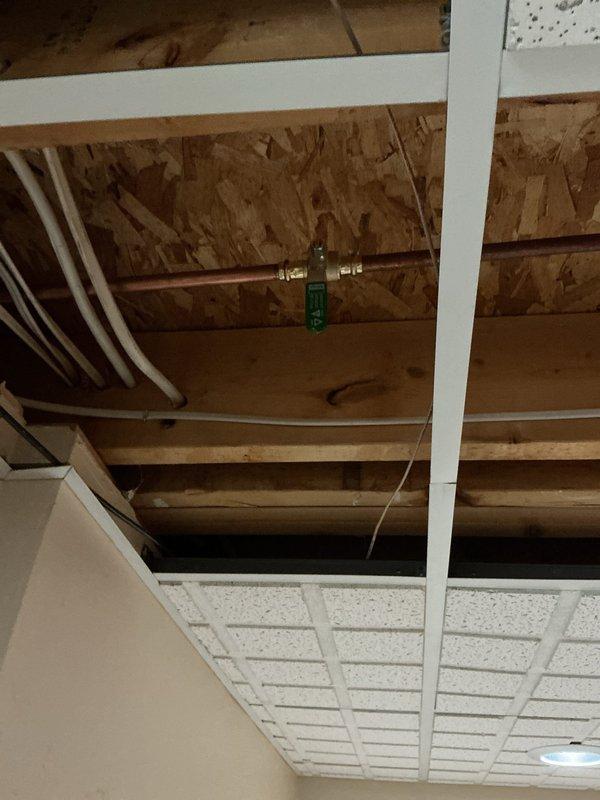 Responded to emergency call for burst copper pipe in 40-year-old home. Upon inspection, identified longitudinal split in aging copper supply line with significant corrosion at fitting connection. Removed damaged ceiling tiles to access affected area, cut out compromised pipe section, and installed new copper pipe segment with appropriate brass fittings to restore water service.