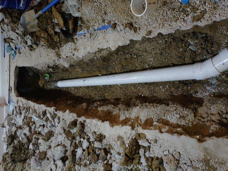 Excavated approximately 20 feet of basement flooring to access and replace a bellied drain line. Installed new solid core PVC piping with code-approved transition bands from the WYE connection feeding the kitchen and stack to the connection before home exit point. Completed camera inspection of the remaining line to verify condition, backfilled the excavated area, and poured new concrete to restore the floor surface.