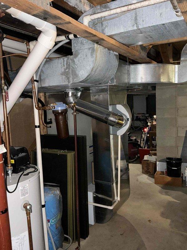Completed estimate for replacement of aging furnace with cracked heat exchanger and outdated water heater. Customer needs to convert from natural gas well supply to propane due to diminishing gas well output. Documented existing installation in utility room showing current ductwork configuration and connection points for proper system replacement planning.