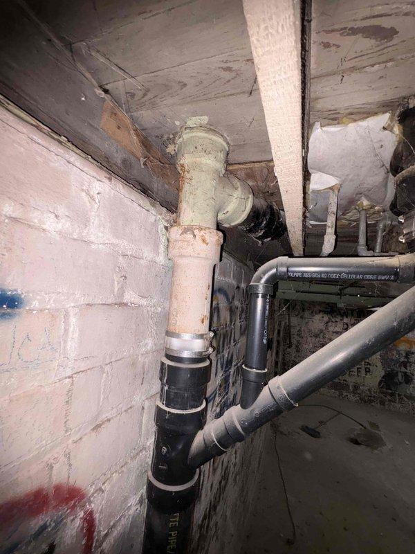 Conducted site assessment of gutted home requiring complete HVAC replacement. Basement inspection revealed significant deterioration with exposed structural elements, damaged concrete flooring, and compromised plumbing system. Noted existing drainage assembly with PVC piping that will need to be integrated with new HVAC installation during upcoming renovation project.