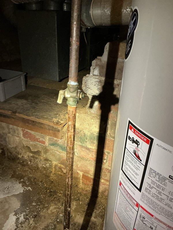 Responded to service call for non-functioning water heater in century-old home. Upon inspection, identified aging copper pipes with significant discoloration connecting to brass valve assembly. Serviced the tank-style water heater system, addressing issues with the ventilation flue and checking multiple shut-off valves to restore proper operation.