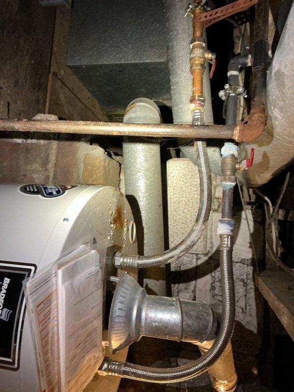Responded to service call for non-functioning water heater in century-old home. Upon inspection, identified aging copper pipes with significant discoloration connecting to brass valve assembly. Serviced the tank-style water heater system, addressing issues with the ventilation flue and checking multiple shut-off valves to restore proper operation.