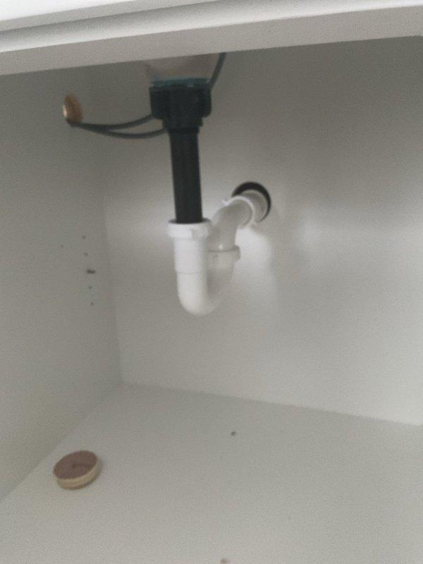 Installed drain assembly for customer's sink, including proper P-trap configuration to prevent sewer gas backflow. Also inspected shower/bath valve fixtures and drain opening in wooden subfloor, which appear to be part of an ongoing bathroom installation project.
