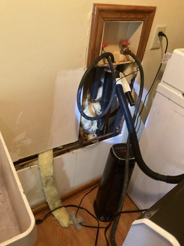 Responded to service call regarding water backup during laundry use. Accessed plumbing system through wall opening near washing machine and inspected drainage line. Located primary cleanout access point in floor and successfully cleared clogged drain line, restoring proper drainage function for laundry system.