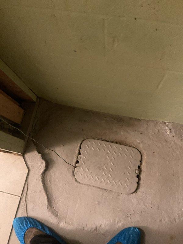 Responded to service call regarding water backup during laundry use. Accessed plumbing system through wall opening near washing machine and inspected drainage line. Located primary cleanout access point in floor and successfully cleared clogged drain line, restoring proper drainage function for laundry system.