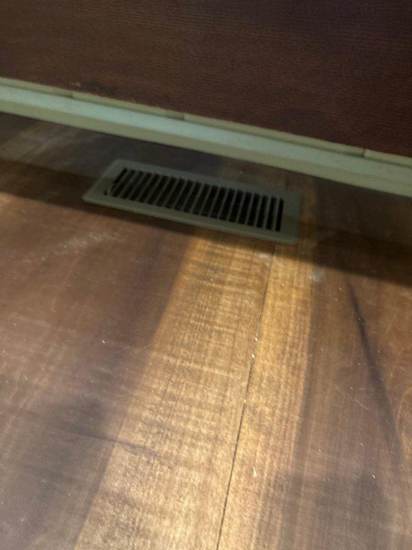 Completed installation of new ductwork system with custom metal fabrication for improved airflow efficiency. Installed floor register in wooden flooring with proper sealing and connection to main trunk line. System was tested and confirmed operational with digital control panel properly calibrated.