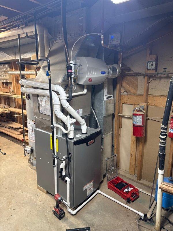 Completed installation of a 90% efficient furnace in basement utility room. System includes new white PVC venting, integrated humidifier, and all required connections. Unit was properly positioned adjacent to existing water heater with appropriate clearances maintained.
