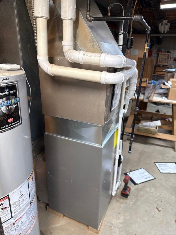 Completed installation of a 90% efficient furnace in basement utility room. System includes new white PVC venting, integrated humidifier, and all required connections. Unit was properly positioned adjacent to existing water heater with appropriate clearances maintained.