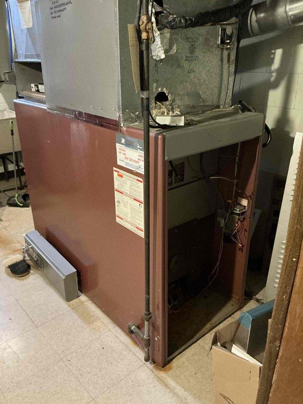Performed inspection of existing heating system that appears to be severely outdated per customer. Current unit shows significant wear with damaged housing, exposed internal components, and insulation protruding through the upper section. Recommended full system replacement due to age-related deterioration and potential safety concerns with the current installation.