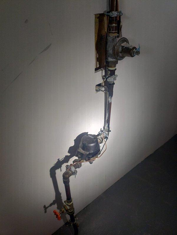 Met with inspector to review electrical panel wiring and plumbing installation. Documented electrical junction box showing multiple wire types (beige, green, pink, black, and red) in metal housing. Also photographed copper pipe assembly with valve configuration, meter gauge, and brass fittings for inspection documentation.