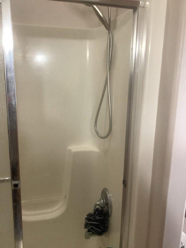 Inspected client's home for reported water heater corrosion and upstairs leak. Examined bathroom shower stall with metal-framed door and flexible shower hose. Evaluated basement plumbing infrastructure, including copper pipes, PVC connections, and pump component, to identify source of leak and assess corrosion damage on hot water tank.