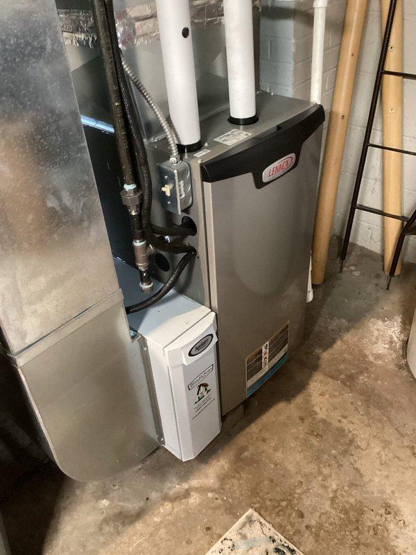 Performed routine MVP heating maintenance service including filter replacement on residential furnace system. Inspected complete HVAC setup including main furnace unit, PVC ventilation pipes, and auxiliary wall-mounted component. System appears properly installed with all connections intact and functioning normally.