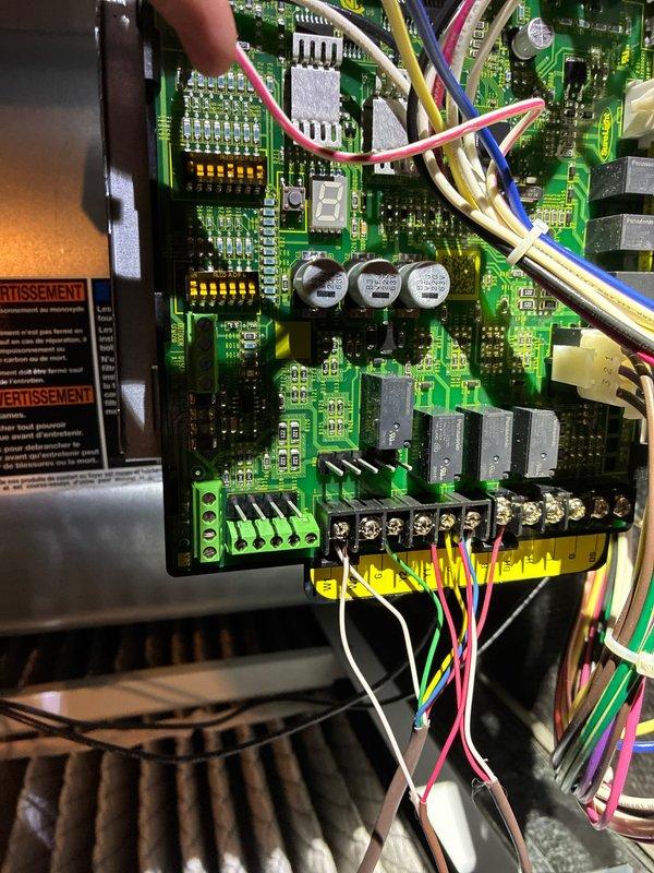 Performed comprehensive furnace tune-up including inspection of the control board circuitry and connections. Examined terminal connections where multiple colored wires (pink, white, yellow, blue, green) interface with the electronic control module. Used hex key tool to make necessary adjustments to system components. All safety warnings and operational parameters were verified during service.