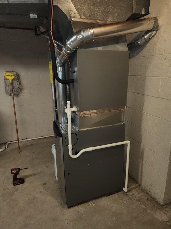Completed installation of 80% efficiency furnace as second phase of HVAC system upgrade. Unit was properly mounted against basement wall with all required ductwork connections established. Installation included proper venting, condensate drainage via PVC piping, and connection of gas line with appropriate shut-off valve. All manufacturer safety labels were preserved and unit was tested for proper operation before completion.