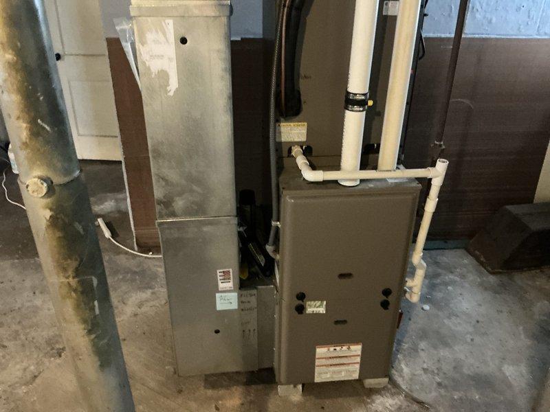 Conducted estimate for replacement of 17-18 year old furnace system in basement utility area. Inspected existing dual-unit HVAC configuration with PVC venting and documented corrosion issues on metal piping. Evaluated ductwork and ventilation system throughout the space, noting glass block window location for potential ventilation considerations.