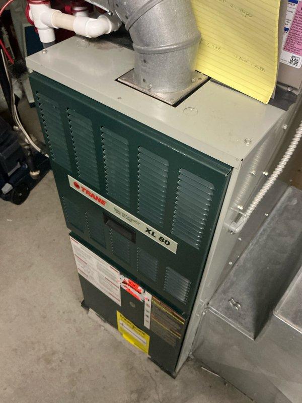Conducted inspection of Trane XL 80 furnace system in basement utility room for replacement estimate. Evaluated existing installation including metal ductwork connections, PVC condensate drainage, and exhaust venting. Noted wall penetration for exhaust duct requires repair work during replacement. Documented current system configuration to prepare comprehensive replacement proposal.