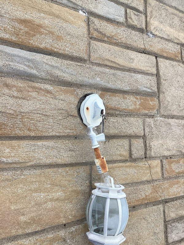 Responded to service call regarding loose exterior electrical wiring with sagging concerns. Upon inspection, found deteriorated wall-mounted light fixture with significant corrosion at connection points and a compromised electrical access point in the masonry wall with exposed wiring. Secured wiring, repaired mounting hardware, and sealed exposed access point to restore safety compliance ahead of approaching storm conditions.