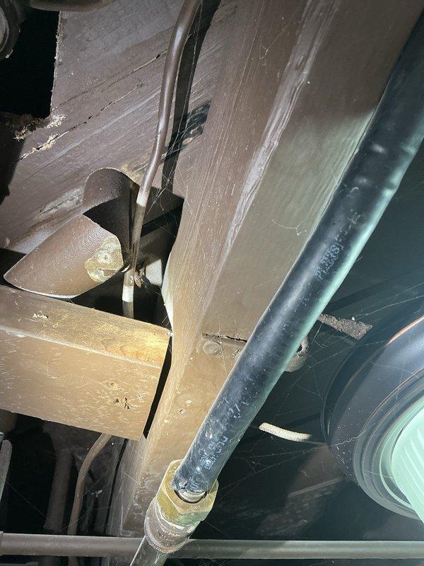 Investigated water leak from main floor bathroom into basement in 1942 home. Visual inspection revealed moisture staining at bathroom fixture base with discoloration where floor tiles meet the porcelain. Further examination of the basement ceiling/joists showed water damage along pipe pathways with visible PVC and copper plumbing lines. Repaired leaking pipe connection and sealed fixture base to prevent future water intrusion.
