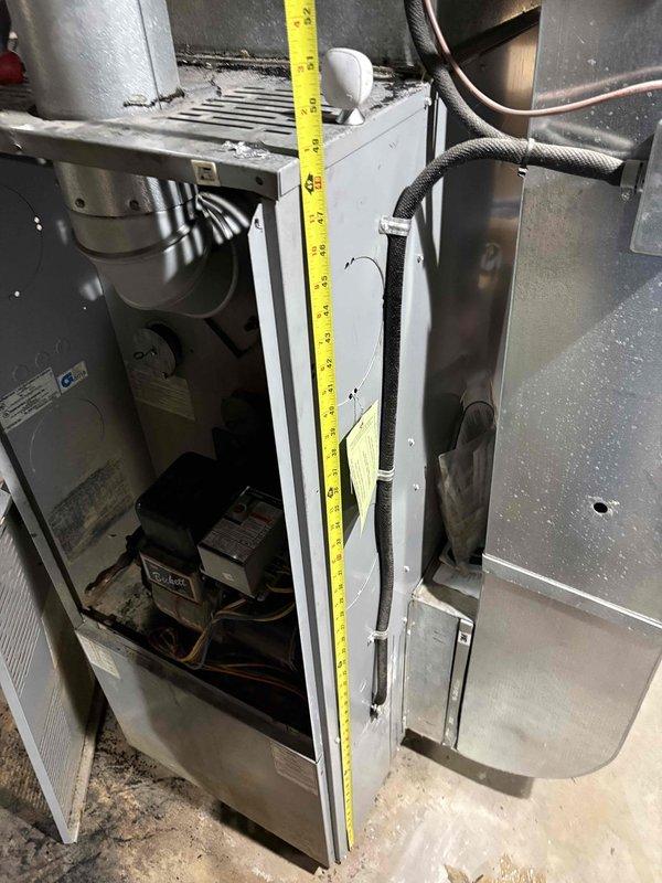 Assessed 26-year-old oil furnace showing significant soot accumulation and deterioration. Performed measurements of existing system to evaluate replacement options. Customer is considering conversion from oil to electric heat pump system with auxiliary heat strips for backup during extreme cold periods.