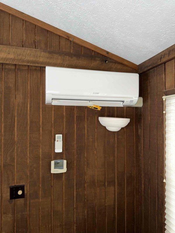 Performed routine maintenance on Mitsubishi mini-split system installed in wood-paneled room. Inspected electrical components including circuit board, wiring connections, and blower motor assembly. Confirmed proper operation of wall-mounted remote control and thermostat.