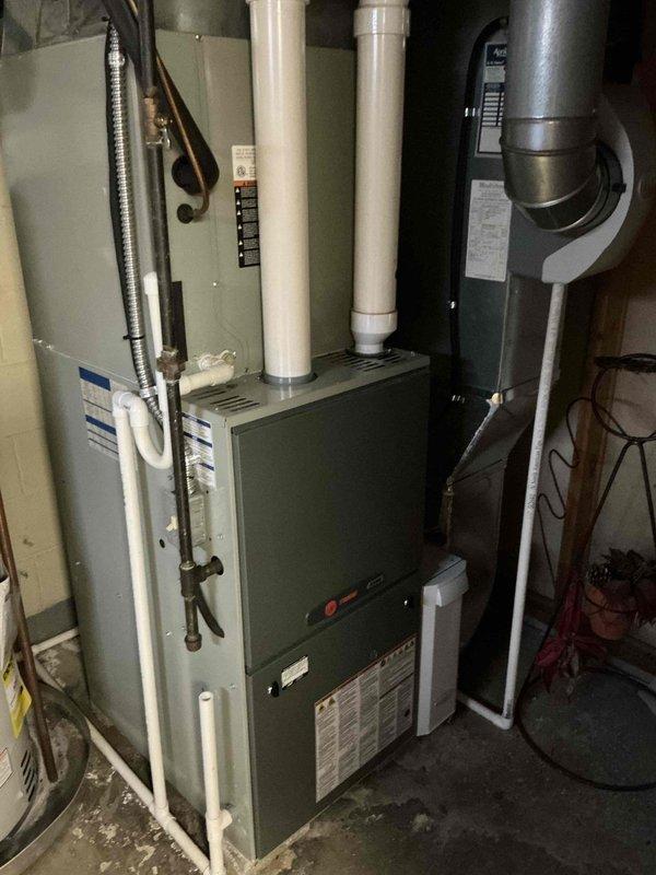 Conducted comprehensive evaluation of existing HVAC system for potential furnace replacement and possible AC installation. Inspected current setup in utility area including furnace unit with associated PVC venting, ductwork connections, and air handler components. Documented condition of galvanized metal duct system, humidifier/condensate pump, and ventilation infrastructure to develop appropriate replacement recommendations.