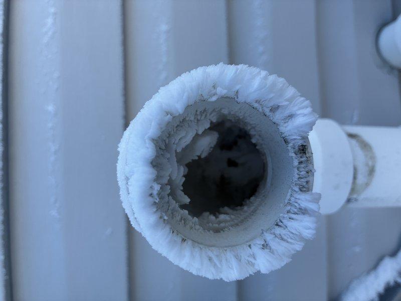 Responded to recurring issue previously serviced by Frank. Observed significant frost buildup around exhaust pipe connection to furnace. Identified frozen condensate drain line with ice formation at exterior wall penetration due to extreme cold temperatures, causing system malfunction. Cleared ice blockage and insulated exterior piping to prevent future freezing.