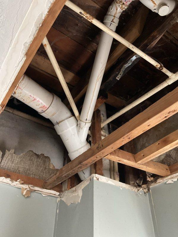 Responded to service call for multiple clogged upstairs drains in century-old home. Upon inspection, discovered deteriorated drain system with significant corrosion in bathtub drain and compromised pipe connections in ceiling infrastructure. Successfully cleared blockage and advised homeowner on recommended repairs to address visible water damage and aging plumbing components.
