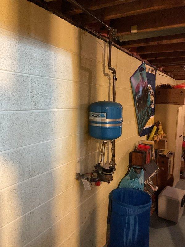 Responded to MVP NAT customer report of basement drain clog. Inspected the basement utility area, which included a vertical waste pipe with brass fitting and nearby expansion tank system. No active intervention was required as inspection revealed normal system operation with no current blockage.