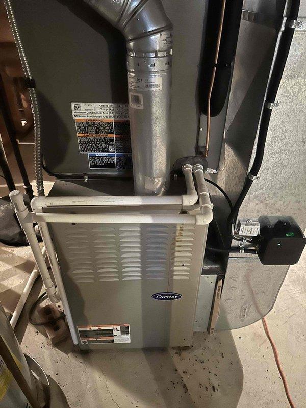 Completed Carrier HVAC system installation with furnace and ductwork in utility area. Secondary auxiliary drain for indoor A-coil was identified as missing during inspection. Installation requires manager approval and re-inspection with photographic documentation to be submitted to county inspector.