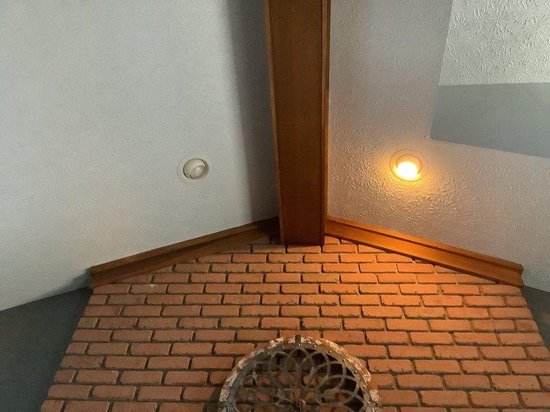 Responded to service call for non-functioning light after customer reported hearing a loud sound. Upon inspection of the vaulted ceiling area, identified damaged recessed lighting fixture in textured ceiling adjacent to brick feature wall. Replaced faulty fixture and tested system to confirm proper operation and no electrical hazards present.