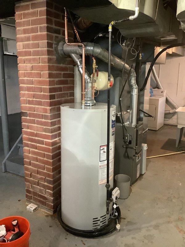 Replaced 40-gallon tall water heater with a new 40-gallon short model Bradford White unit, creating necessary clearance for installation of thermal expansion tank on cold water line. Replumbed gas line using 1/2" pipe from the existing 1/2" x 3/8" 90° fitting above ductwork to the tank and installed new 1/2" shut-off valve. Complete installation includes new ball valve and 6-year tank warranty.