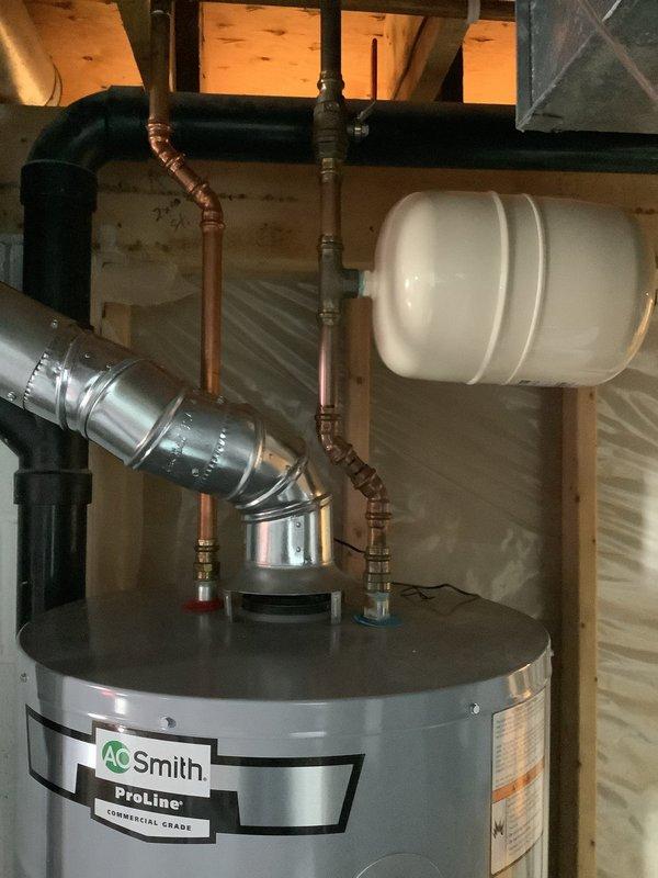 Responded to customer concern regarding improper venting on A.O. Smith ProLine commercial grade water heater. Inspected existing installation which included copper piping, expansion tank, and metal ductwork. Verified and corrected ventilation system to ensure proper exhaust routing through metal vent pipe that extends from heater top and angles appropriately across ceiling joists, bringing installation into compliance with safety standards.