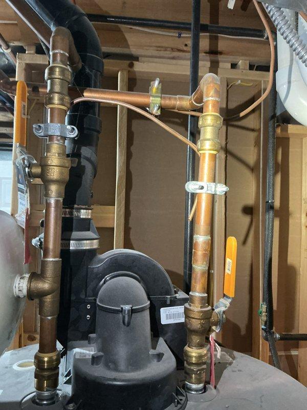 Responded to service call to provide estimate for natural gas water heater replacement. Inspected existing unit in basement utility area, which included a cylindrical tank with expansion tank mounted on top. Documented current plumbing configuration including copper supply lines, PVC/ABS drain pipes, and associated valves and fittings to prepare accurate replacement quote.